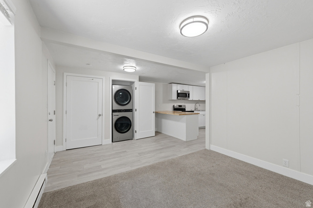 831 Lennox Street, Unit 5 Midvale, UT 84047 - Photo 8 of 19 Laundry area featuring baseboard heating, stacked washing machine and dryer, and light carpet