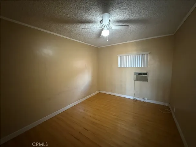 an empty room with wooden floor chandelier fan and windows