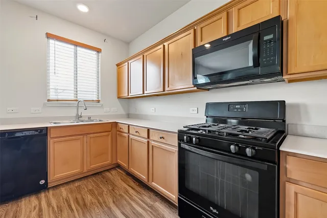 a kitchen with stainless steel appliances a sink a stove a microwave cabinets and a window