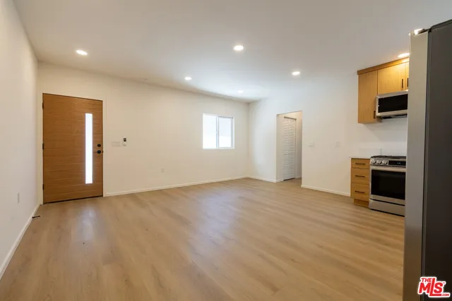 a view of an empty room with wooden floor and a window