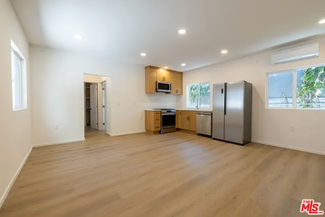 a kitchen with stainless steel appliances a refrigerator a sink and wooden floors