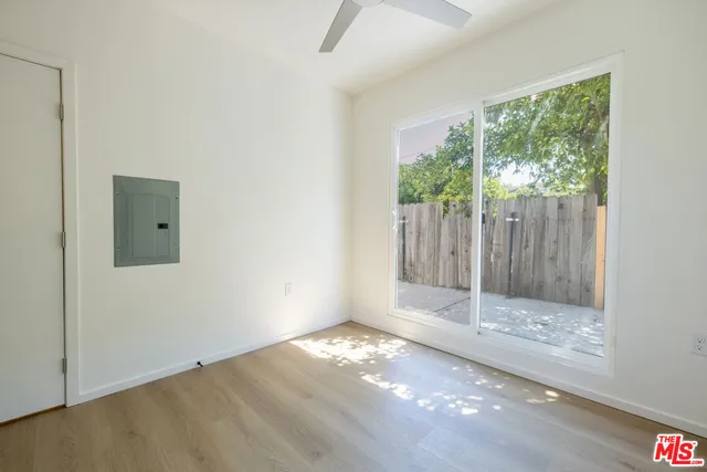 a view of empty room with wooden floor and fan