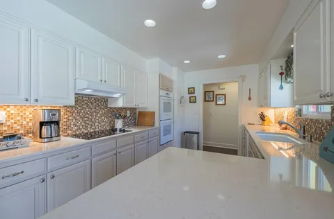 a kitchen with granite countertop a sink stove and cabinets