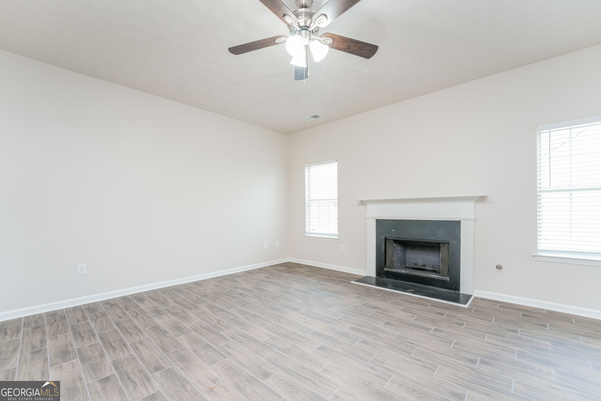 15 Emerson Trail Covington, GA 30016 - Photo 2 of 17 an empty room with windows fireplace and fan
