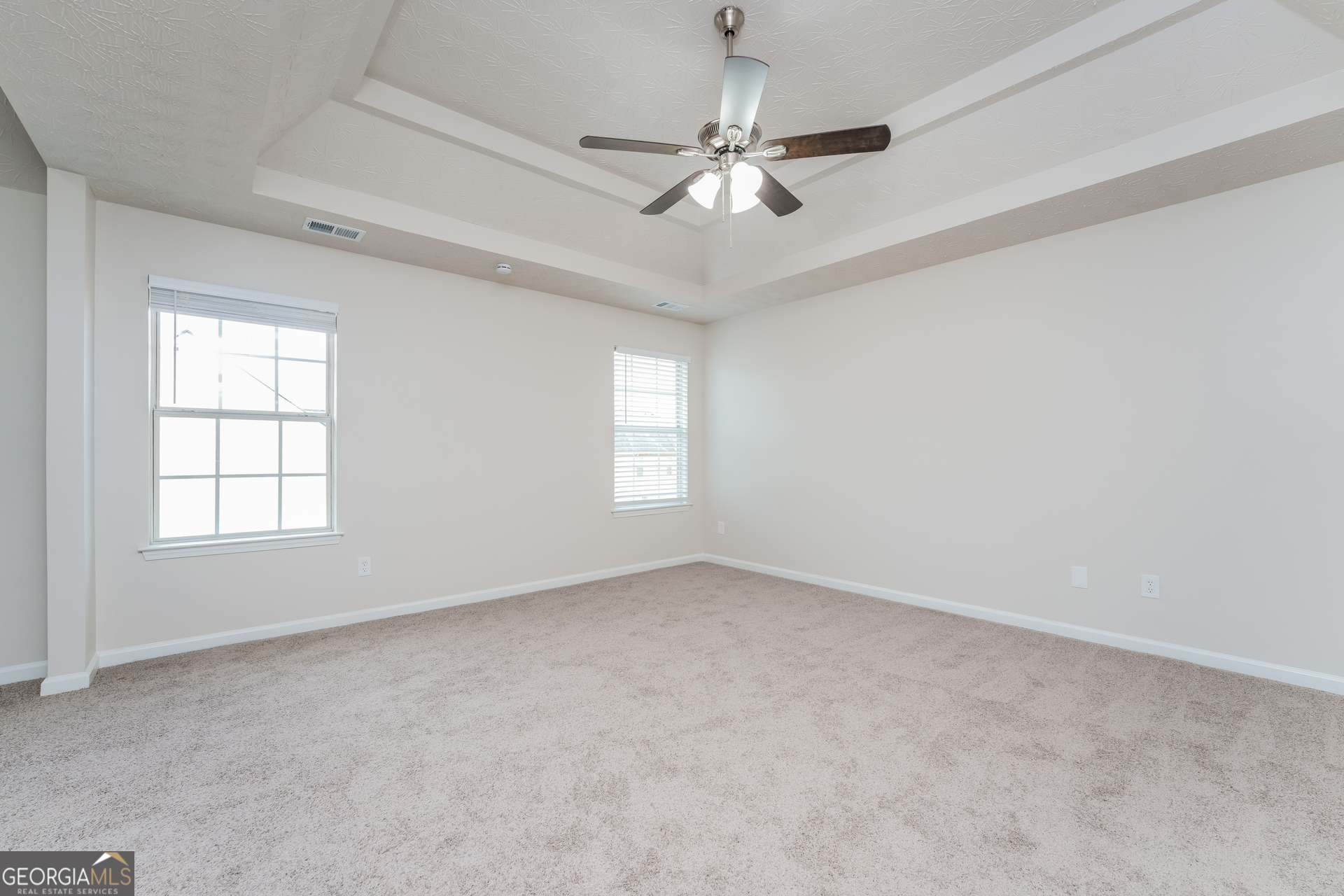 15 Emerson Trail Covington, GA 30016 - Photo 8 of 17 an empty room with a chandelier fan and windows