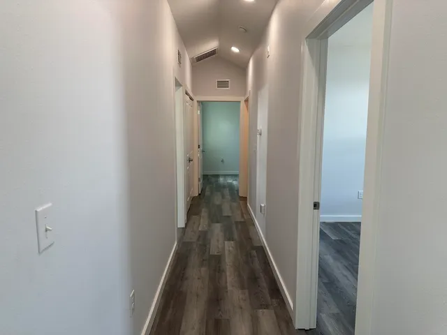 a view of a hallway with wooden floor and a bathroom