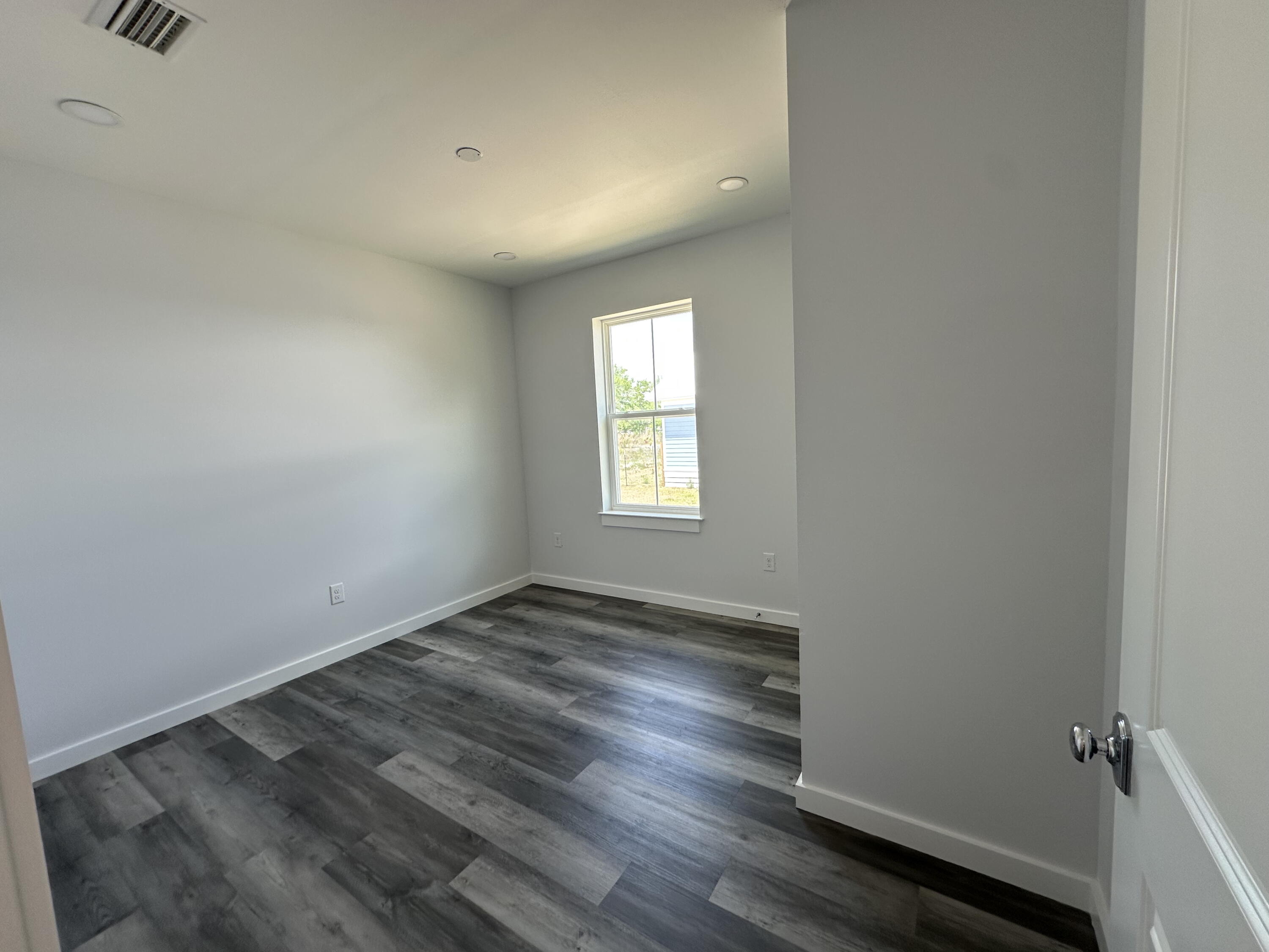 534 North Raphael Road DeFuniak Springs, FL 32433 - Photo 10 of 20 an empty room with wooden floor and windows