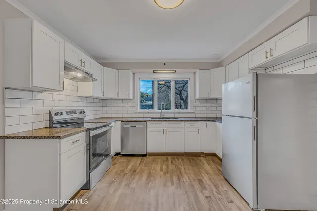 a kitchen with a sink a refrigerator and white cabinets