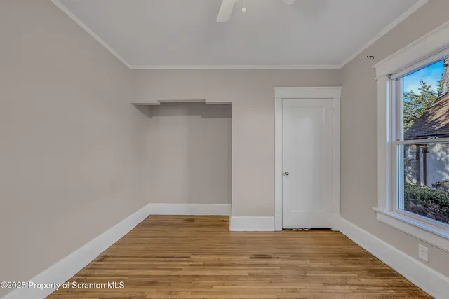 a view of an empty room with window and wooden floor