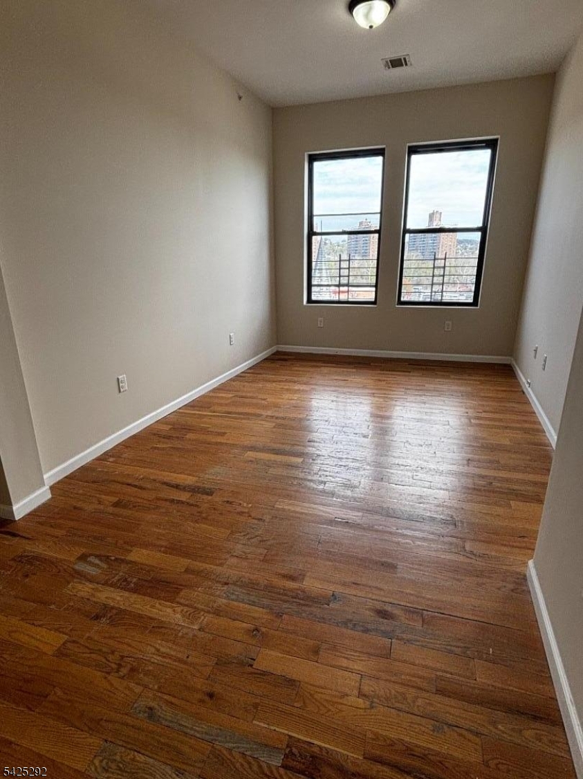 40 Broadway, Unit 5B Paterson, NJ 07505 - Photo 3 of 7 an empty room with wooden floor and windows