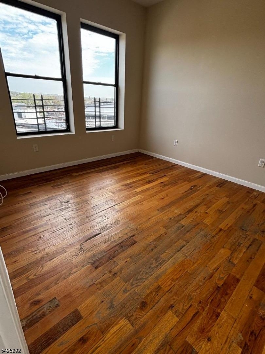 40 Broadway, Unit 5B Paterson, NJ 07505 - Photo 5 of 7 an empty room with wooden floor and windows