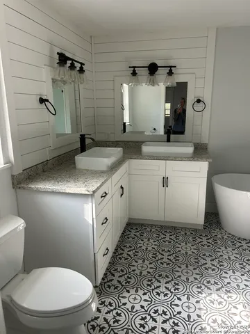 a bathroom with a granite countertop sink mirror vanity and toilet