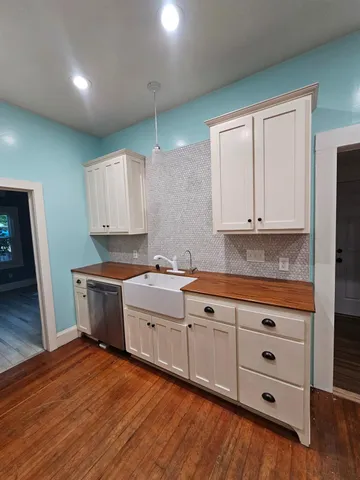 a kitchen with granite countertop white cabinets and wooden floor