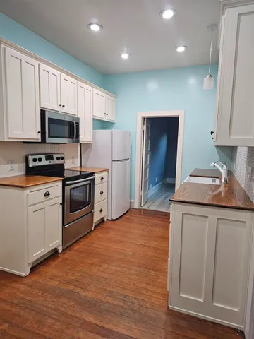 a kitchen with stainless steel appliances granite countertop a refrigerator a stove top oven a sink and dishwasher with wooden floor