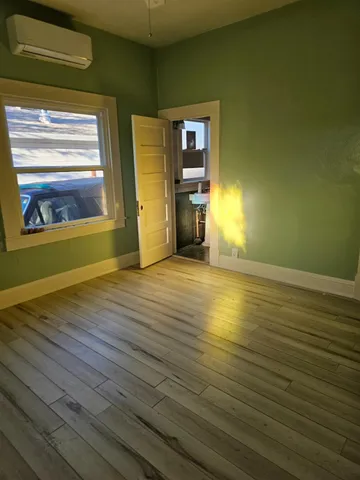 a view of a hallway with wooden floor and a cabinet