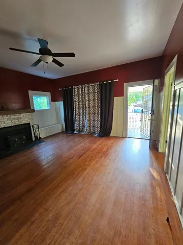 a view of a livingroom with wooden floor a ceiling fan and a kitchen