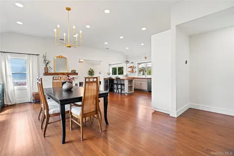 a living room with stainless steel appliances kitchen island wooden floor and fireplace