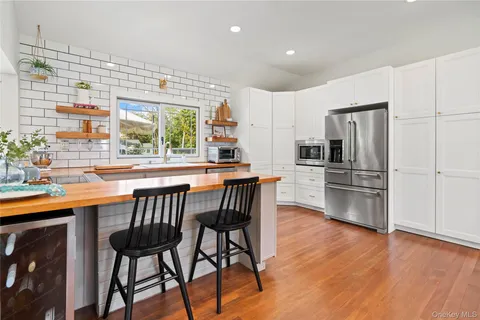 a kitchen with stainless steel appliances wooden floor and chairs
