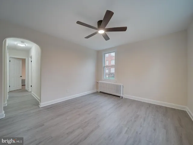 an empty room with wooden floor a ceiling fan and windows