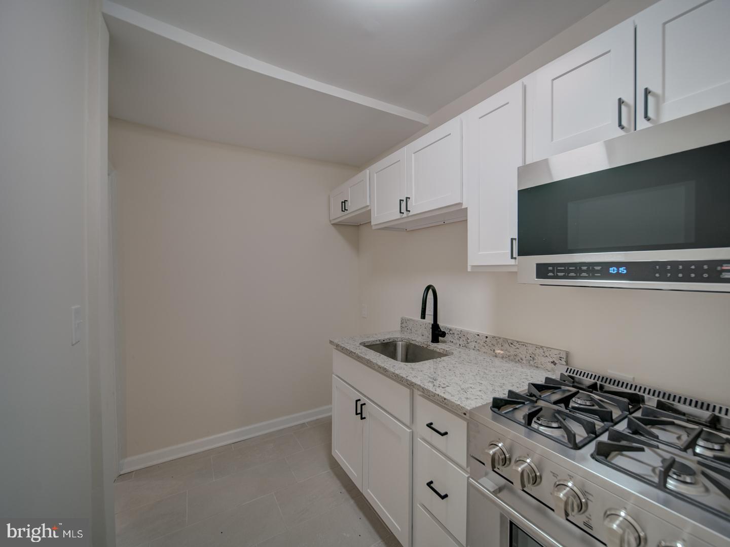 1946 I Street Northeast Washington, DC 20002 - Photo 16 of 47 a kitchen with granite countertop a sink and a stove top oven