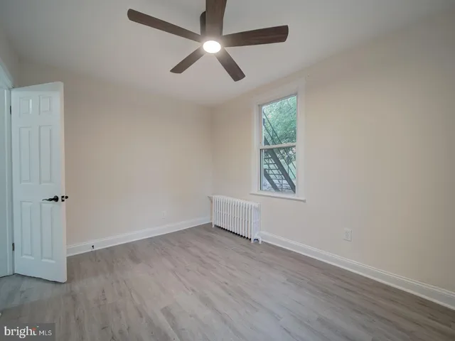 an empty room with wooden floor ceiling fan and windows