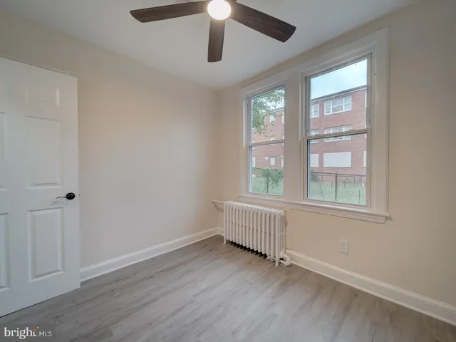 an empty room with wooden floor fan and windows