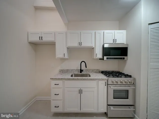 a kitchen with white cabinets and appliances