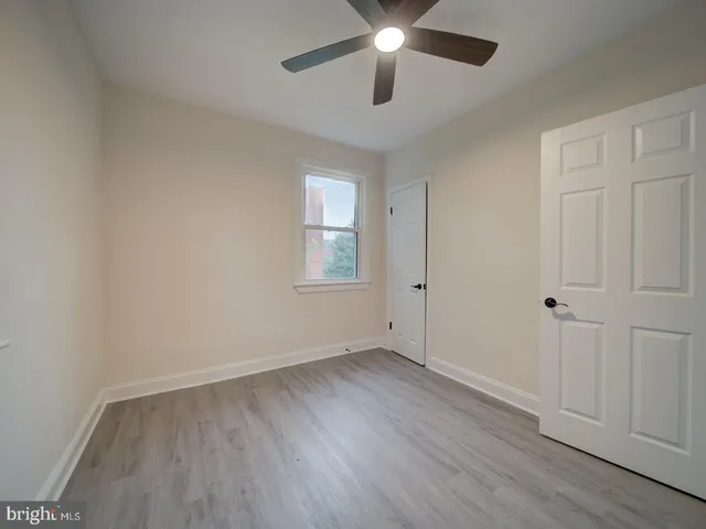 an empty room with wooden floor chandelier fan and windows