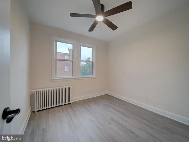 an empty room with wooden floor fan and windows