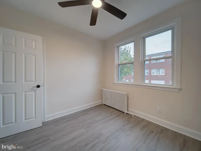 a view of an empty room with wooden floor and window