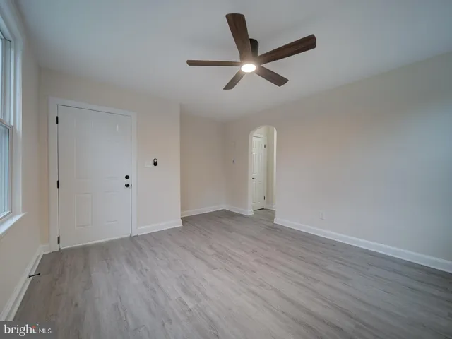 an empty room with wooden floor ceiling fan and windows