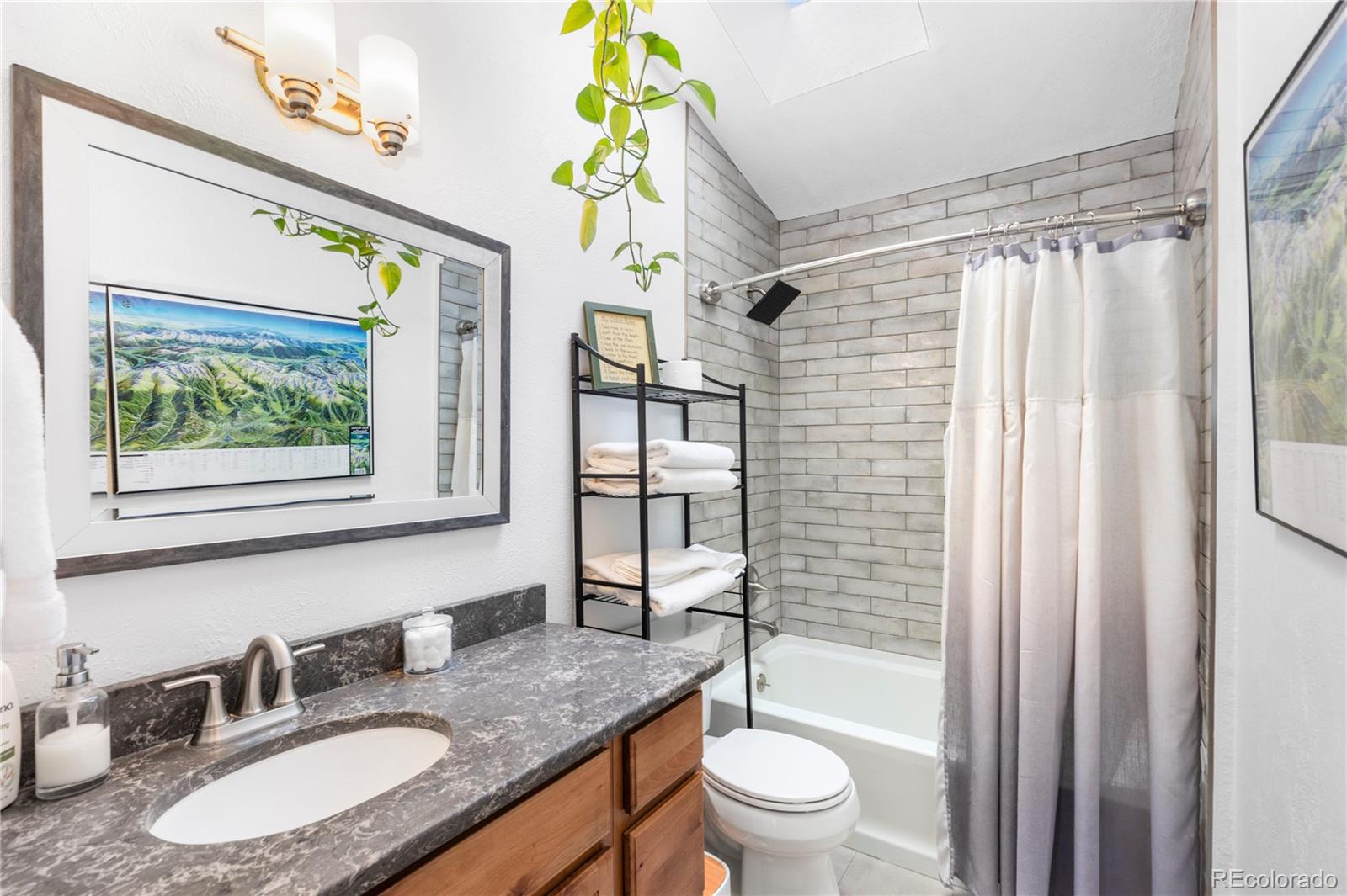 10221 Blue Sky Trail Conifer, CO 80433 - Photo 32 of 37 a bathroom with a granite countertop sink a toilet a mirror a vanity and shower