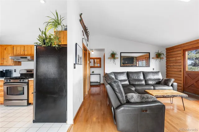 a living room with stainless steel appliances granite countertop furniture a refrigerator a stove a sink and a window