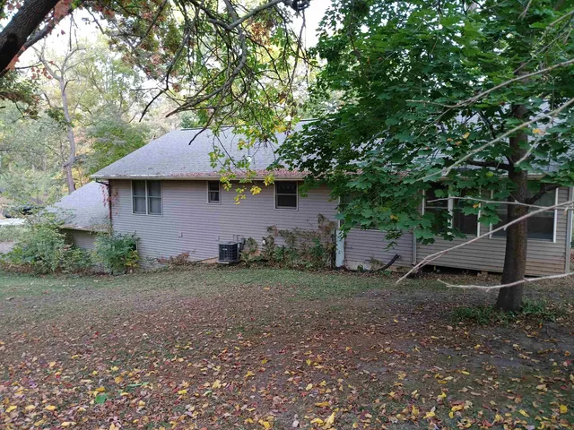 a backyard of a house with plants and large tree