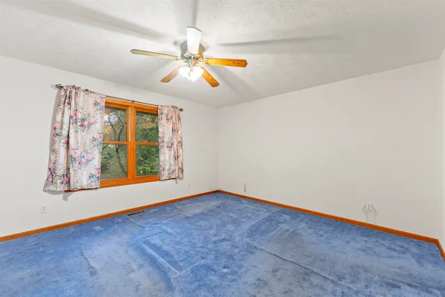 an empty room with window and ceiling fan