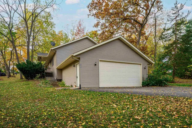 a small white house with a small yard and large trees