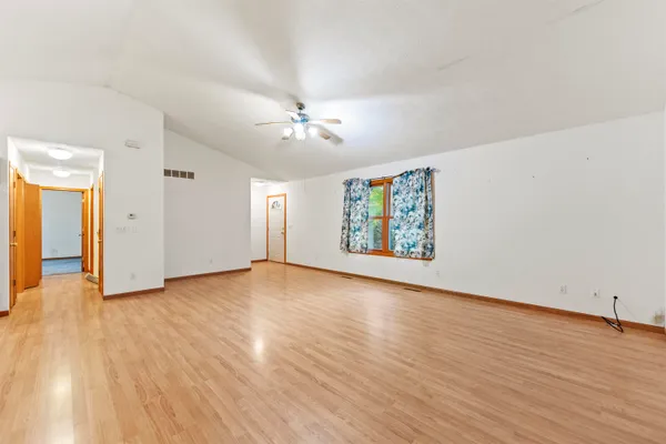 an empty room with wooden floor fan and windows