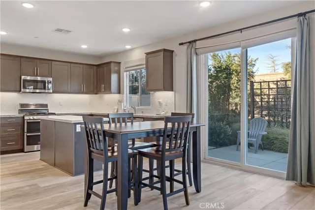 a kitchen with stainless steel appliances granite countertop a stove a refrigerator a microwave a dining table and chairs