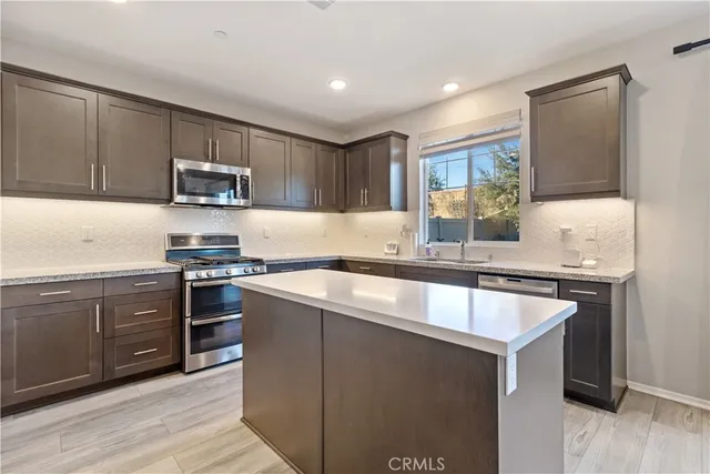 a kitchen with kitchen island granite countertop a sink stove and microwave
