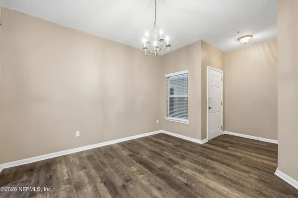 a view of an empty room with window and wooden floor