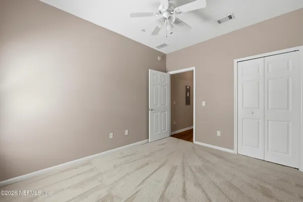 a view of an empty room with a chandelier fan