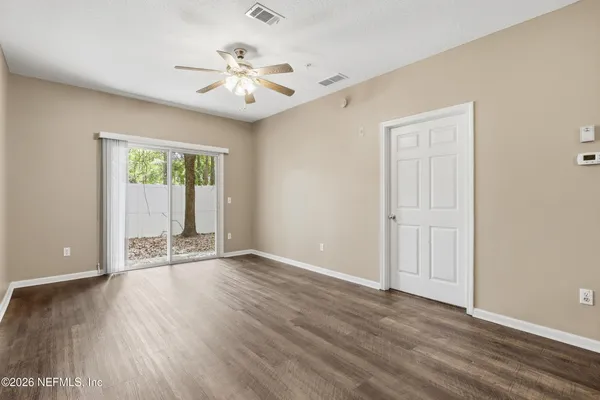 a view of an empty room with wooden floor and a window