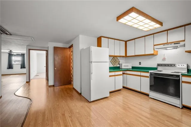 a kitchen with granite countertop wooden floors and white stainless steel appliances