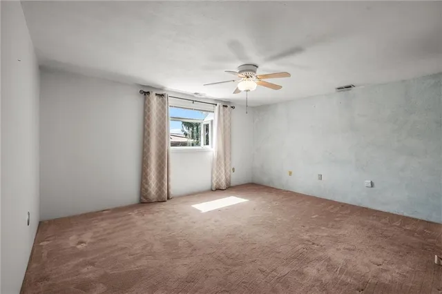 an empty room with windows and chandelier fan