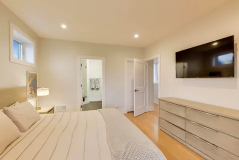 a spacious bedroom with a bed and a flat screen tv