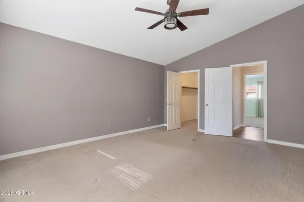 a view of a room with a ceiling fan and carpet