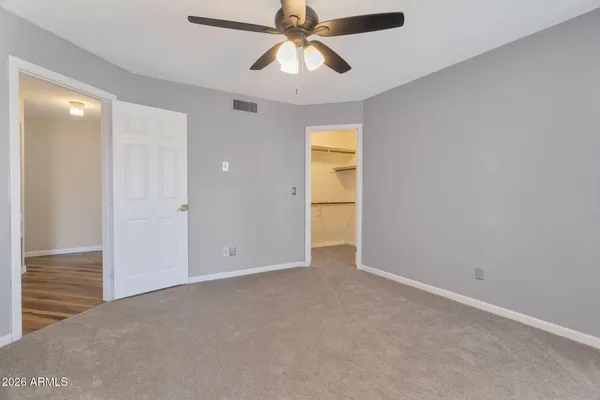 a view of an empty room and chandelier fan