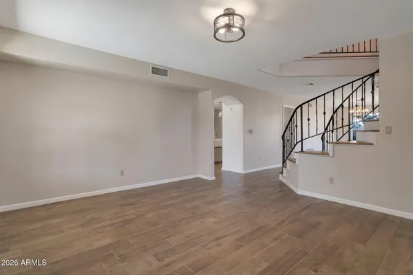 a view of an empty room with wooden floor and stairs