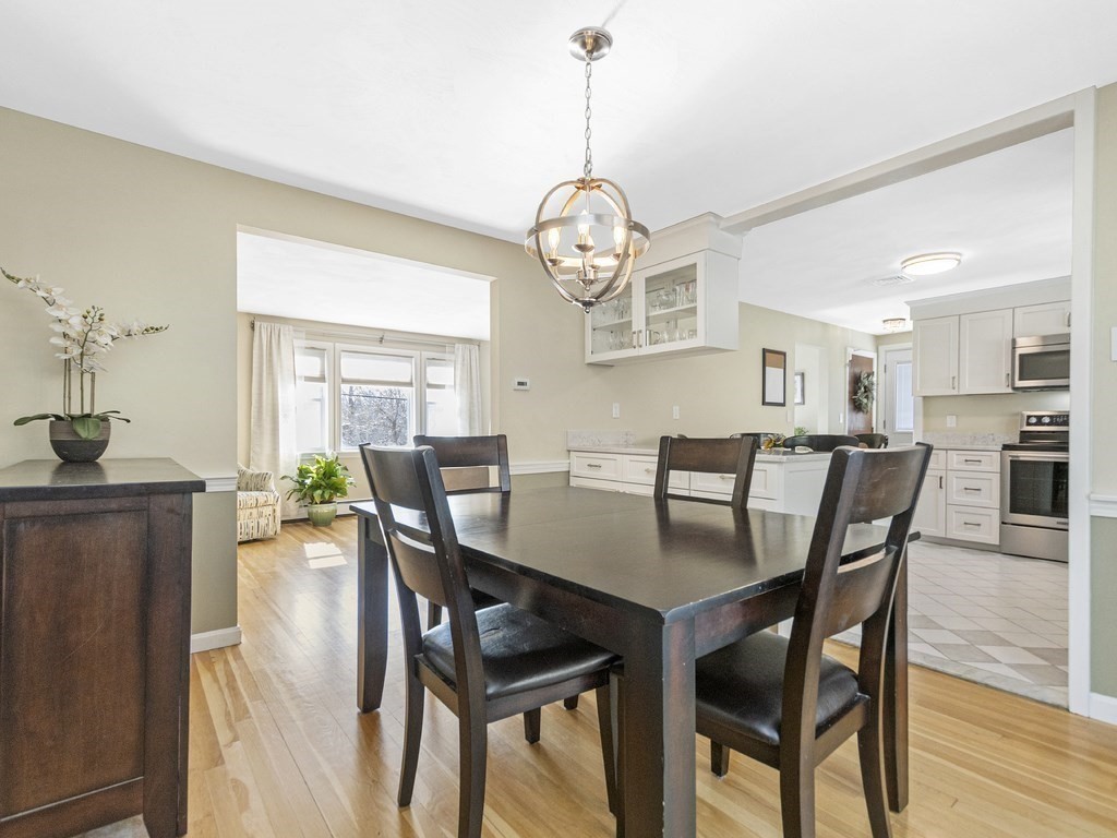 223 Hardy Pond Road Waltham, MA 02451 - Photo 16 of 38 a view of a dining room and livingroom with furniture wooden floor a rug a potted plant and a chandelier