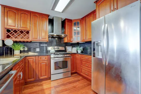 a kitchen with stainless steel appliances granite countertop a refrigerator a sink dishwasher a stove with wooden cabinets and floor